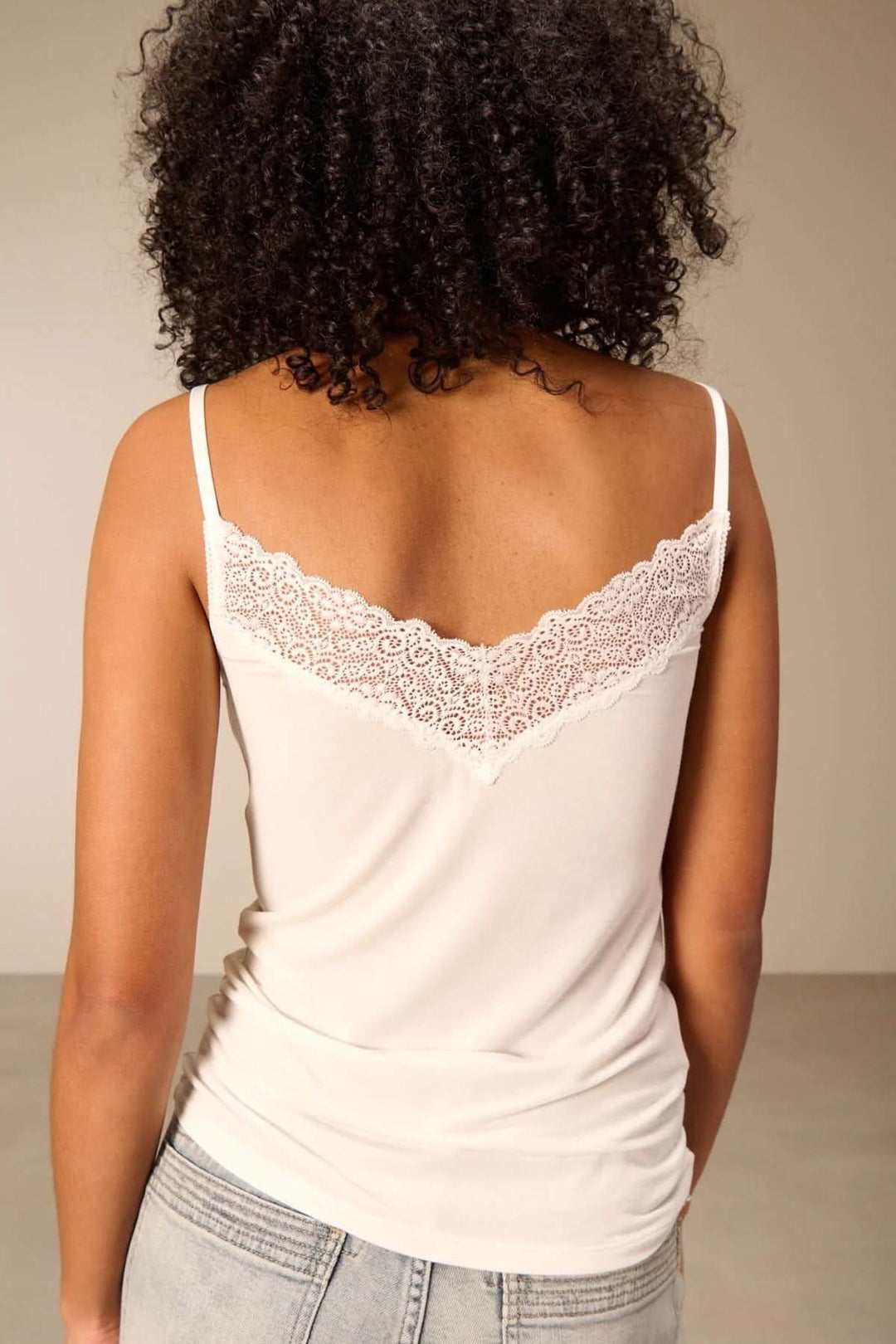 Vue arrière de la camisole à bretelles avec dentelle, encolure en V en dentelle fine, portée sur un mannequin avec un jean clair.