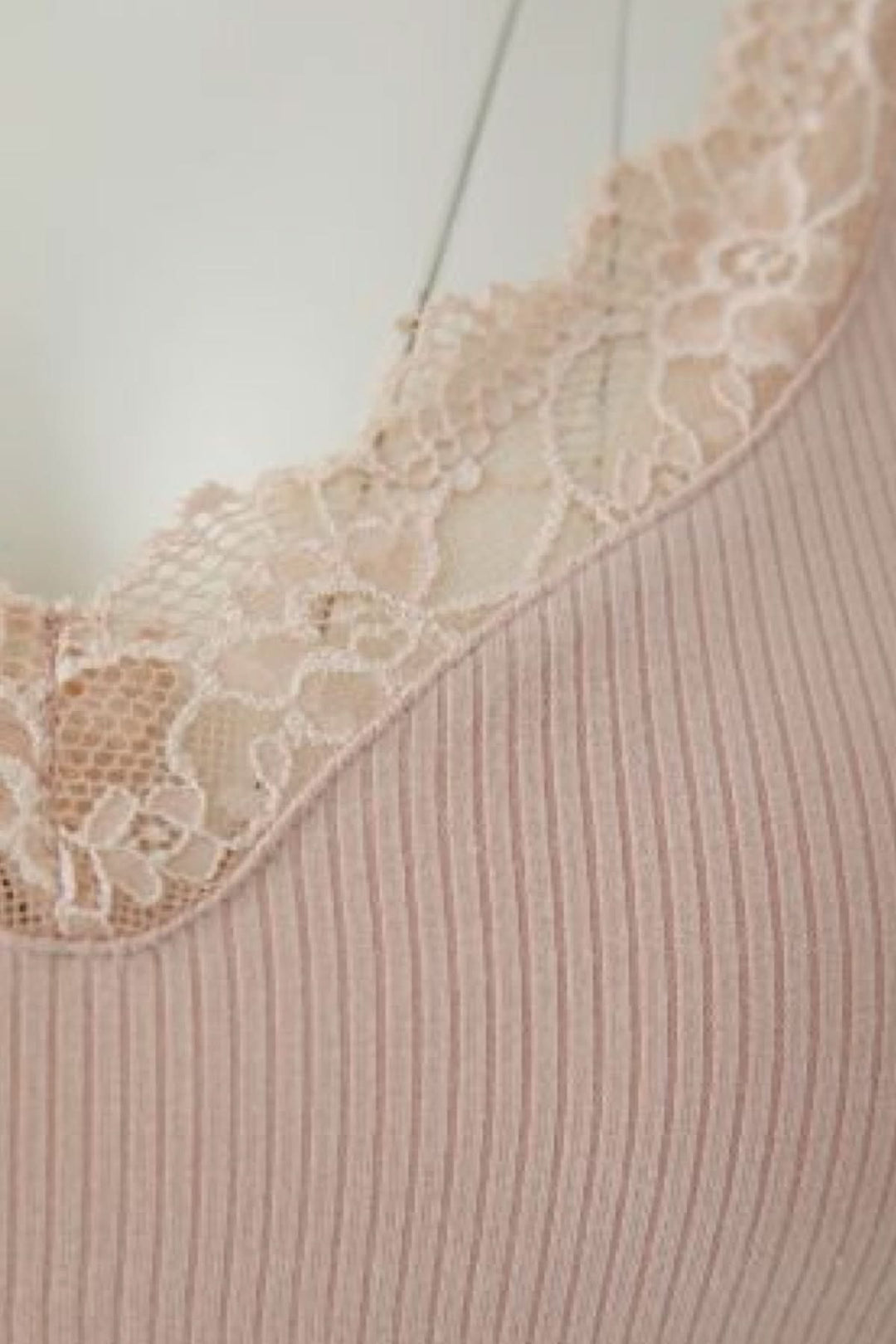 Camisole côtelée à bretelles fines avec encolure en dentelle montrant le tissu extensible et le design minimaliste.