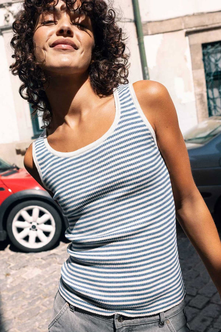 Femme portant une camisole côtelée rayée col rond en plein air, soulignant un style moderne et ajusté pour une journée active.