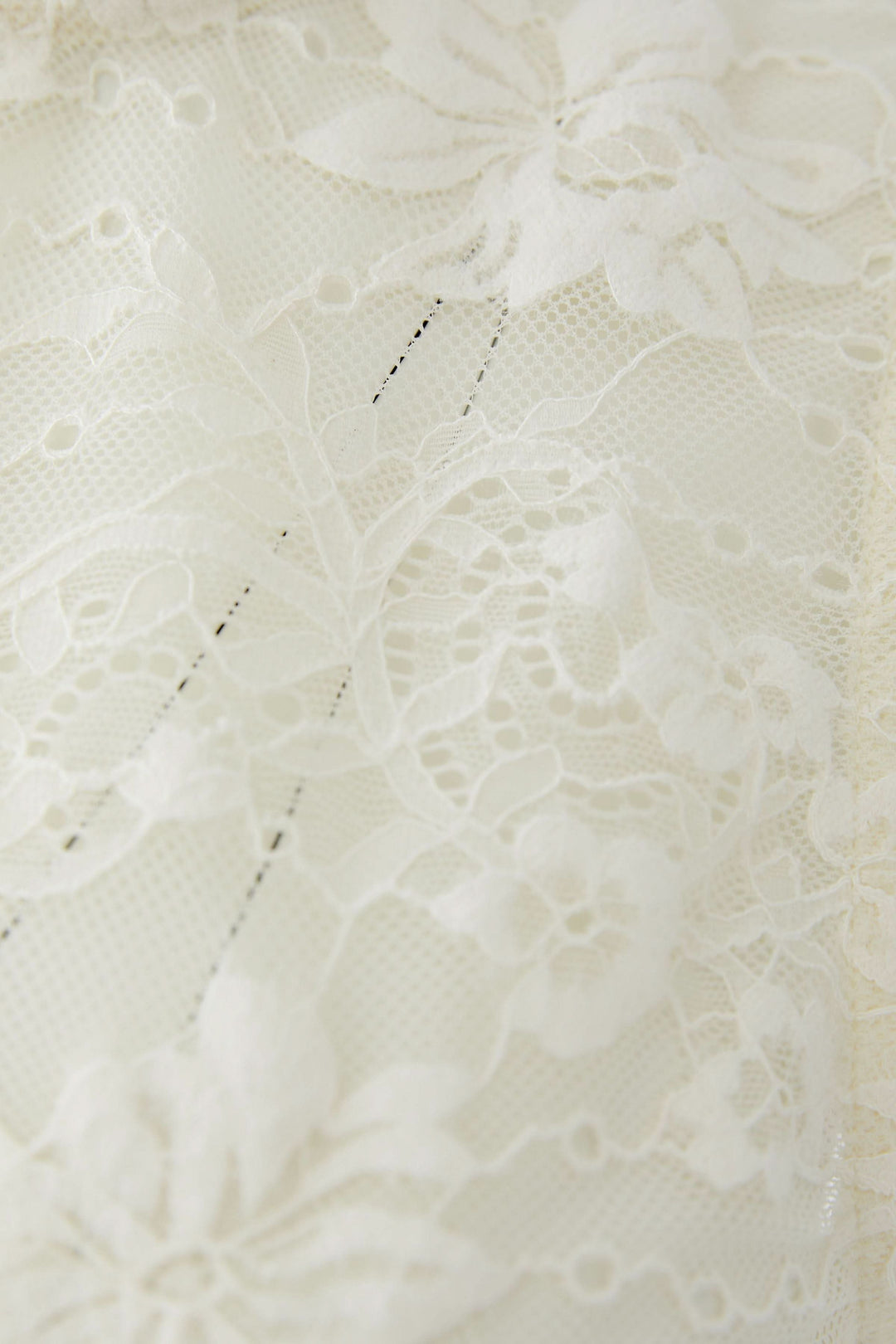 Détail de la dentelle florale délicate de la camisole en dentelle florale avec motif élégant et féminin.