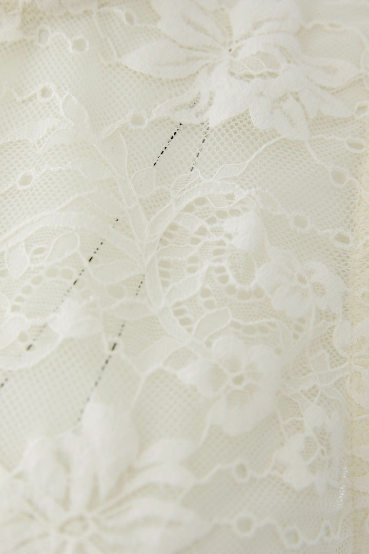 Détail de la dentelle florale délicate de la camisole en dentelle florale avec motif élégant et féminin.