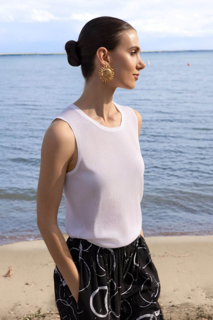 Femme portant une camisole en maille texturée au bord de la mer, style épuré et moderne.