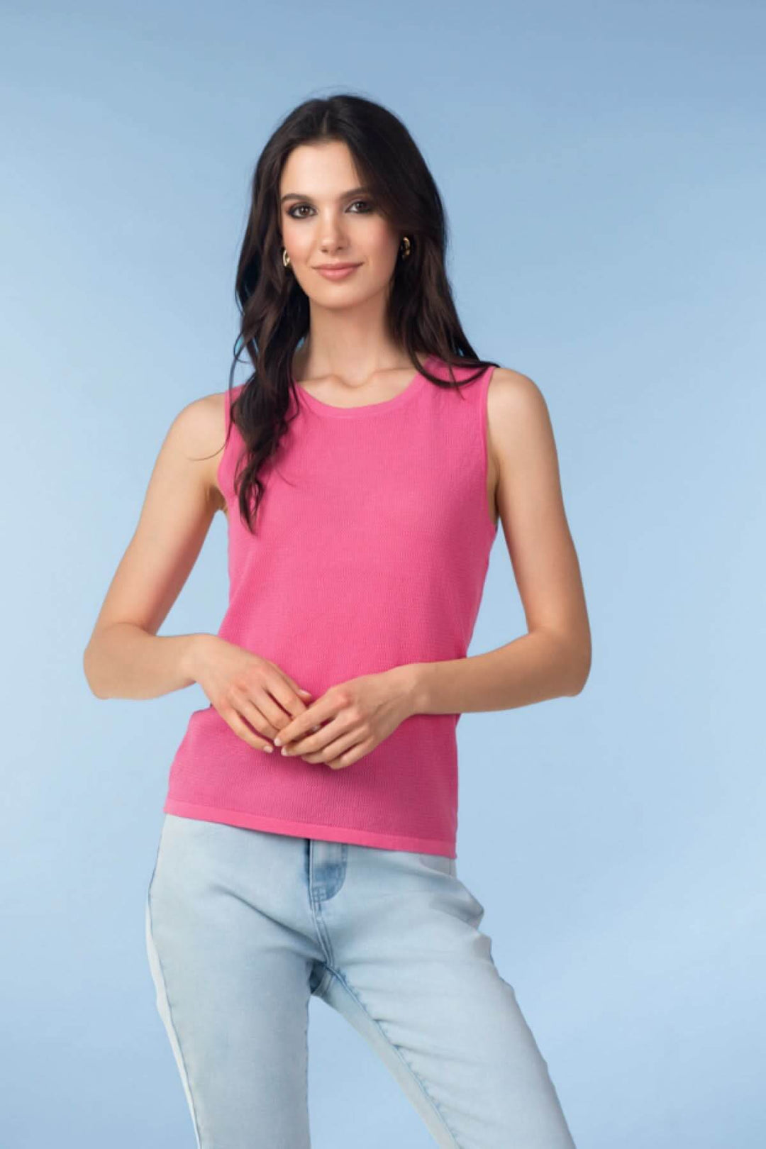 Femme portant une camisole en maille texturée rose avec un style épuré et moderne, idéale pour un look soigné au quotidien.