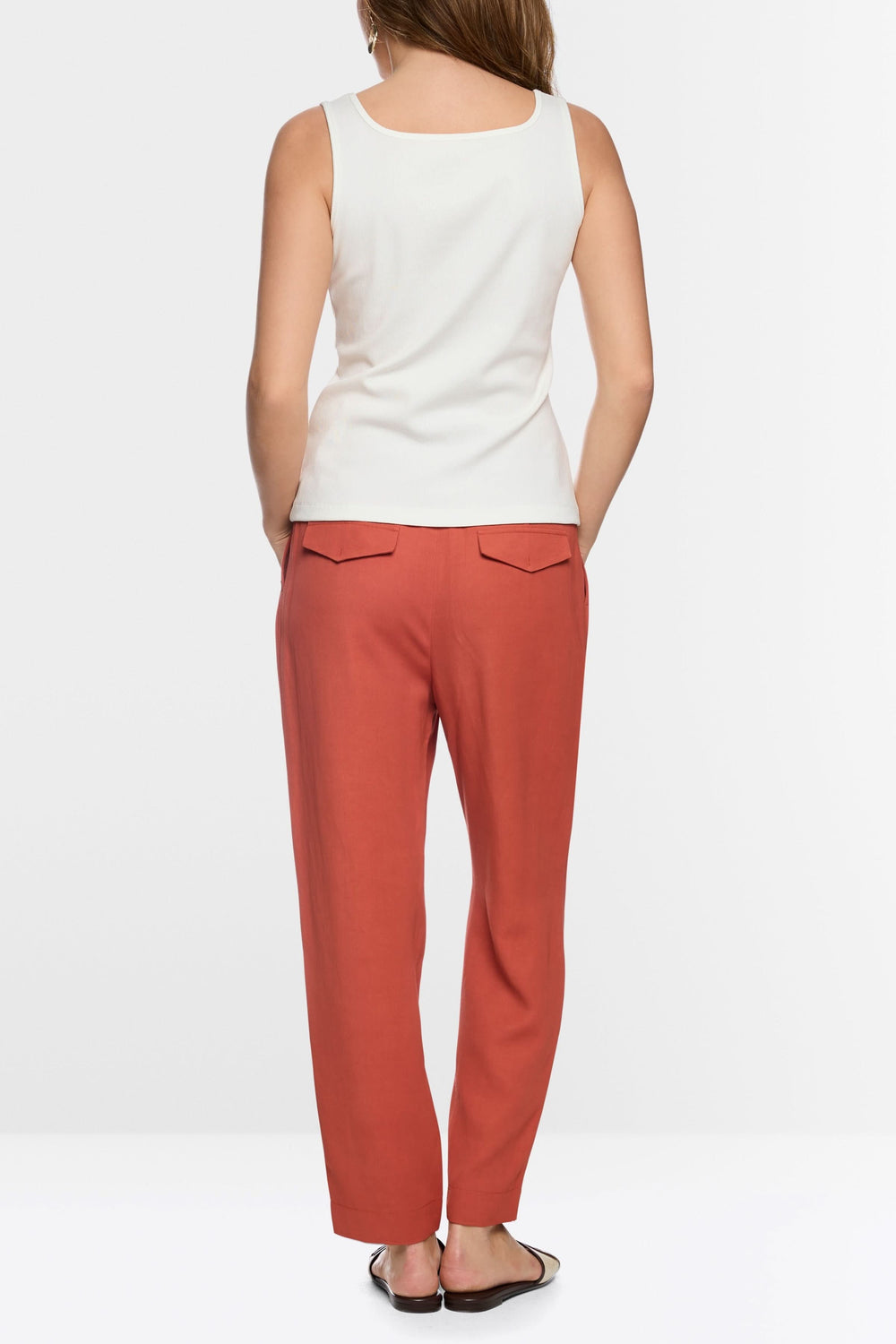 Camisole à encolure carrée blanche avec bretelles larges, portée avec un pantalon rouge. Tissu doux et extensible, silhouette moderne.