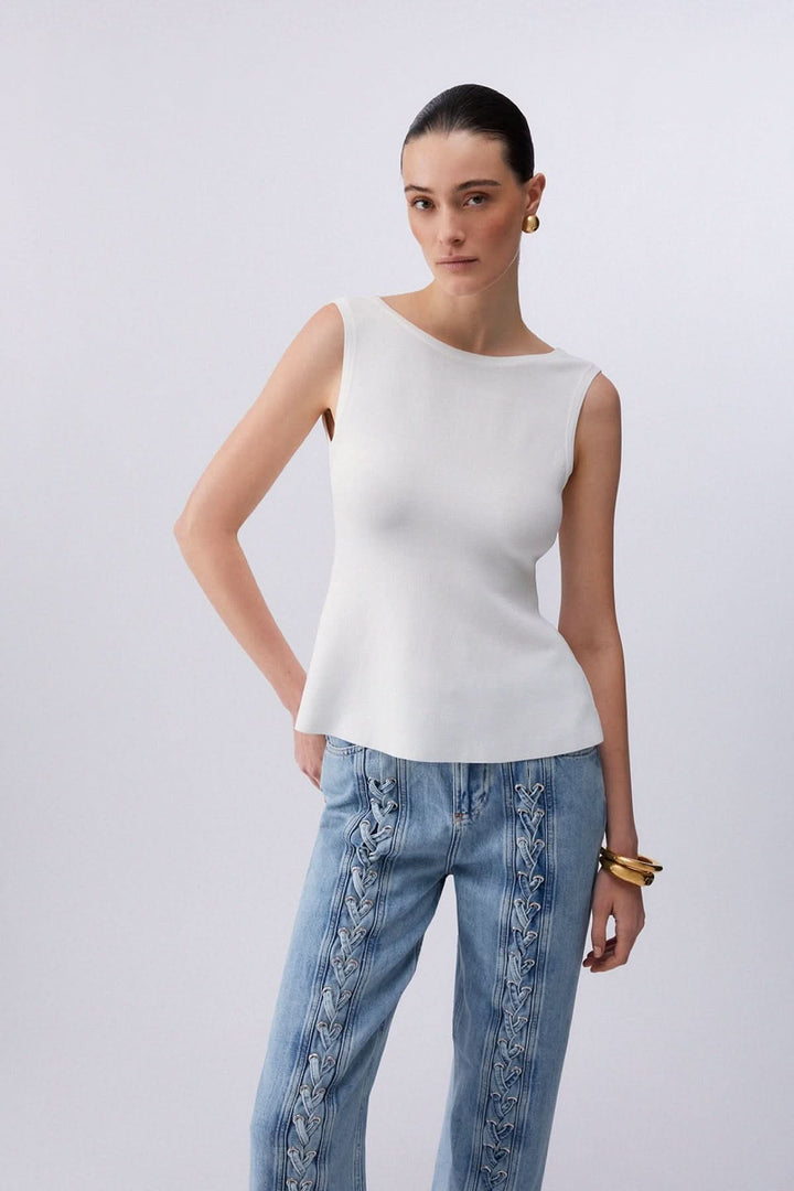 Femme portant une camisole fluide avec dos ouvert et nœud, encolure bateau, coupe fluide, style moderne.