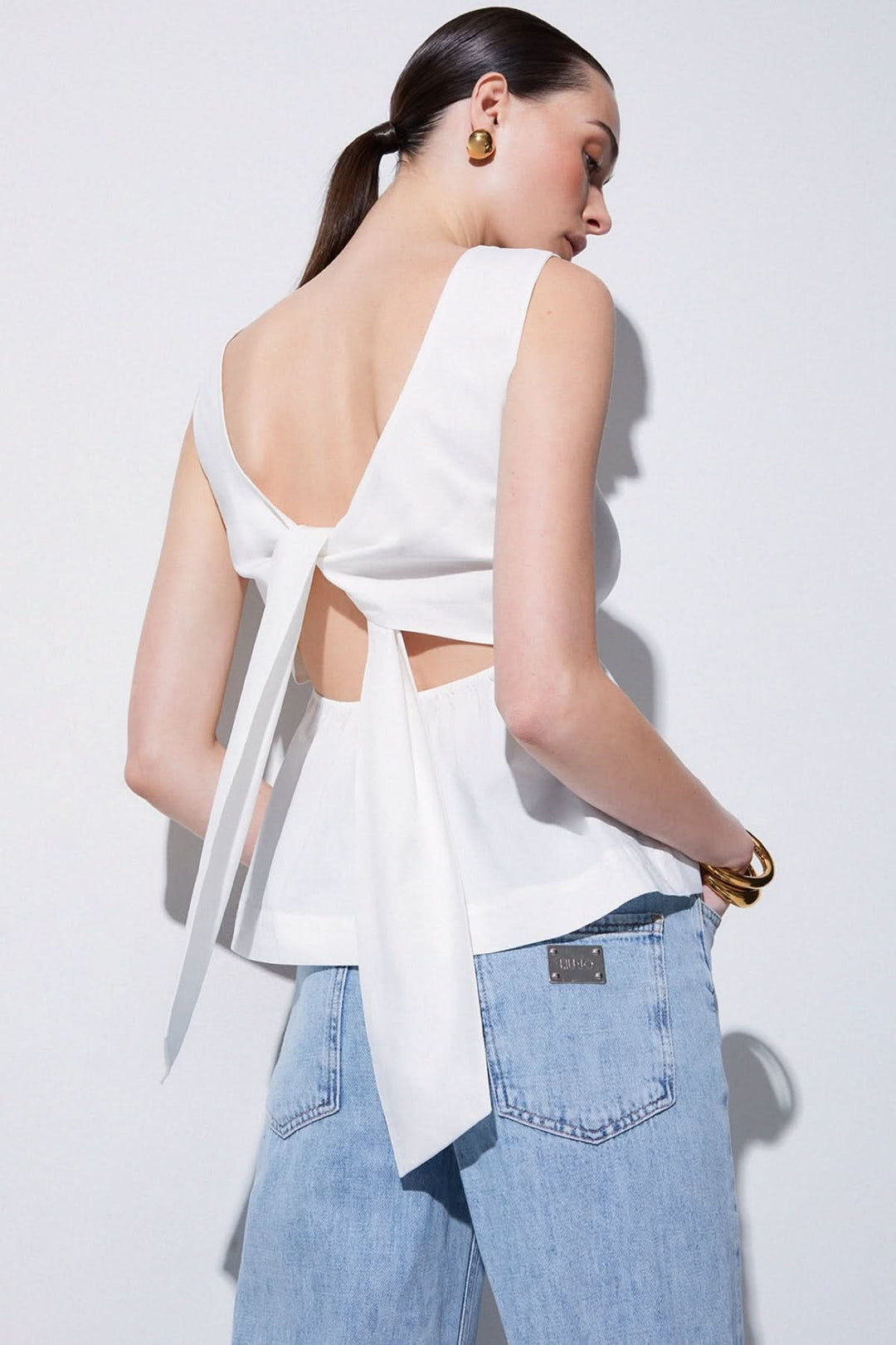 Camisole fluide avec dos ouvert et nœud, élégante et confortable avec encolure bateau, idéale pour superpositions légères et modernes.