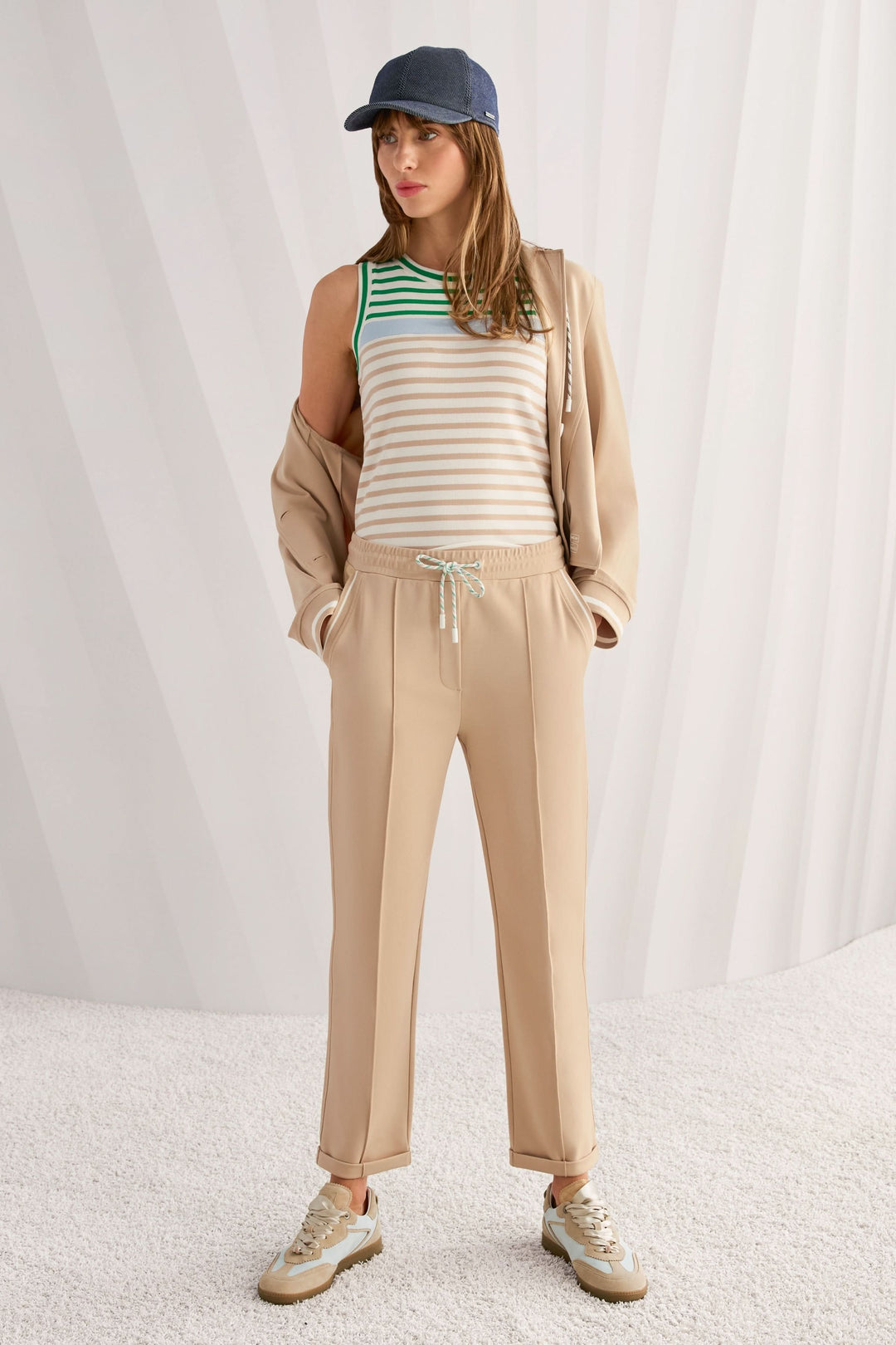 Femme portant une camisole rayé en coton avec encolure ronde et pantalon beige, look décontracté.