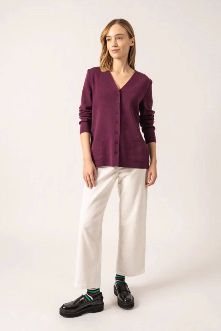 Cardigan Blainville en maille fine, col V, boutons en métal, porté avec un pantalon blanc et des chaussures noires.