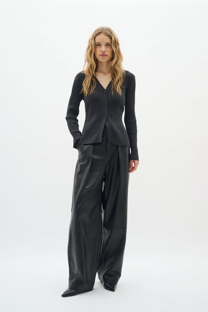 Cardigan Gia à côtes fines, encolure en V, porté avec un pantalon noir pour un look chic et élégant.