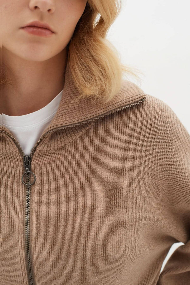 Femme portant un cardigan en laine avec col montant et fermeture zippée, idéal pour un look décontracté.