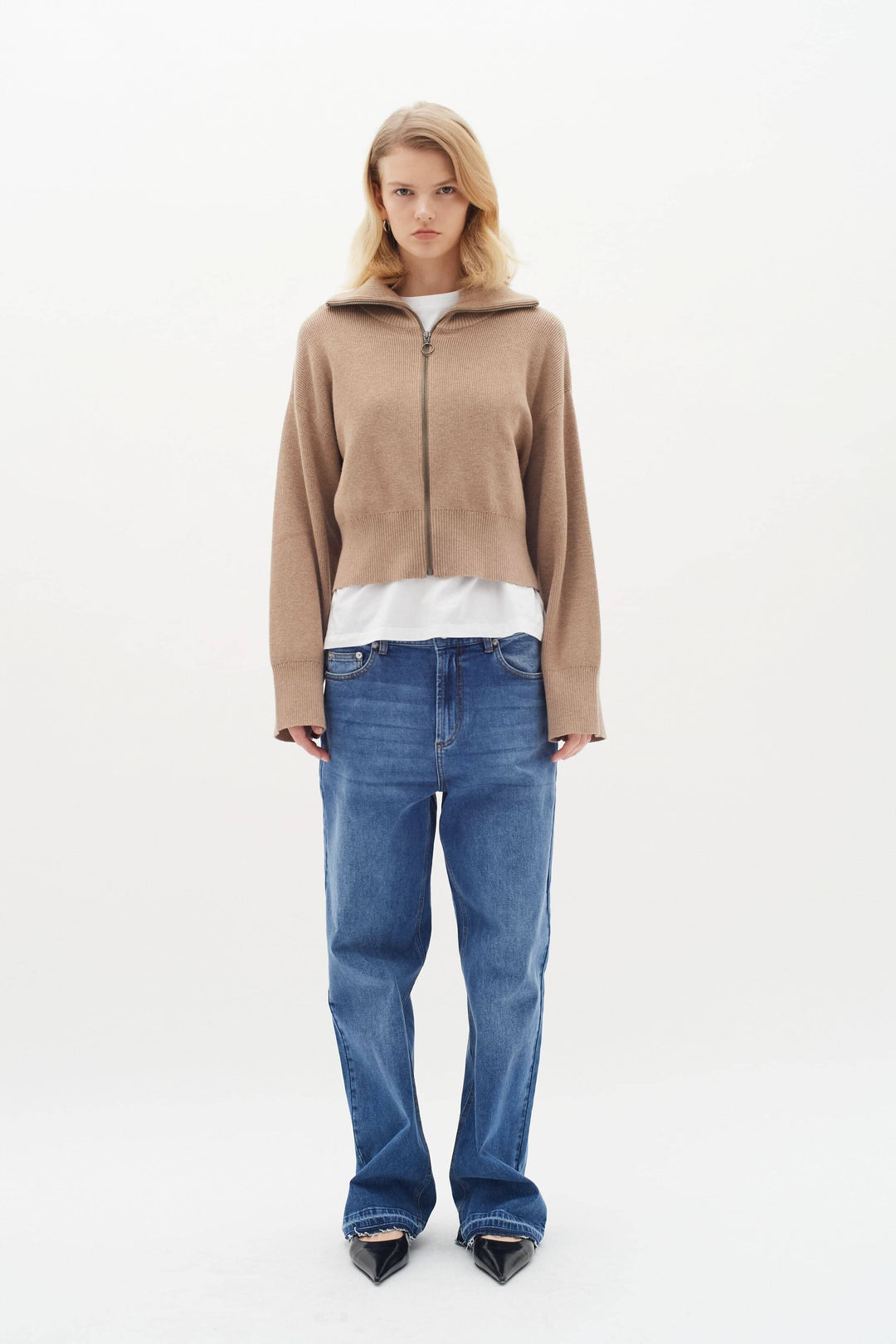 Femme portant un cardigan Jogan zippé, col montant, avec un t-shirt blanc et un jean droit, style casual-chic.