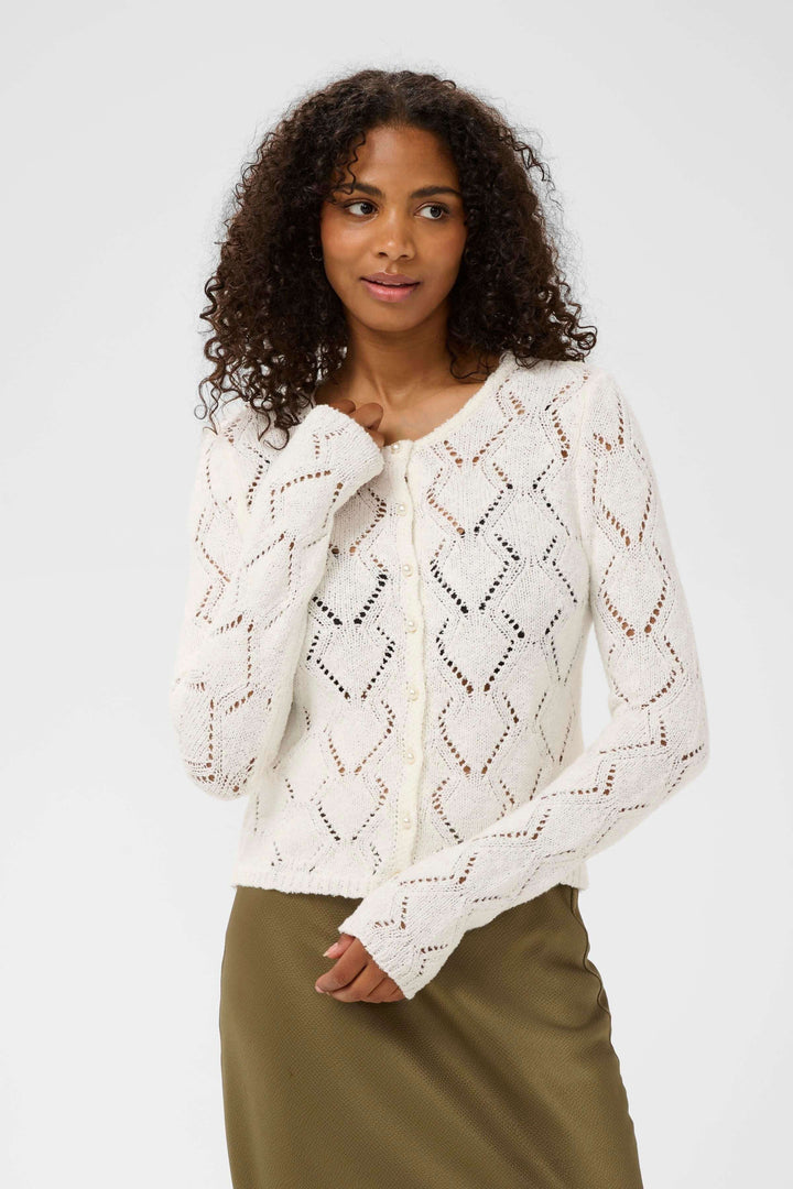 Cardigan Lorinia en maille ajourée, silhouette féminine avec manches longues et fermetures boutonnées, élégant et confortable.