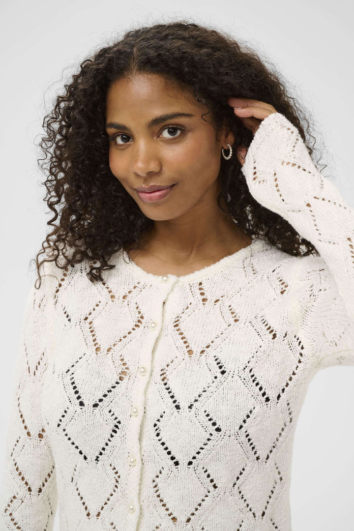 Femme portant un cardigan Lorinia en maille ajourée avec manches longues et fermeture boutonnée, ajoutant élégance et confort.