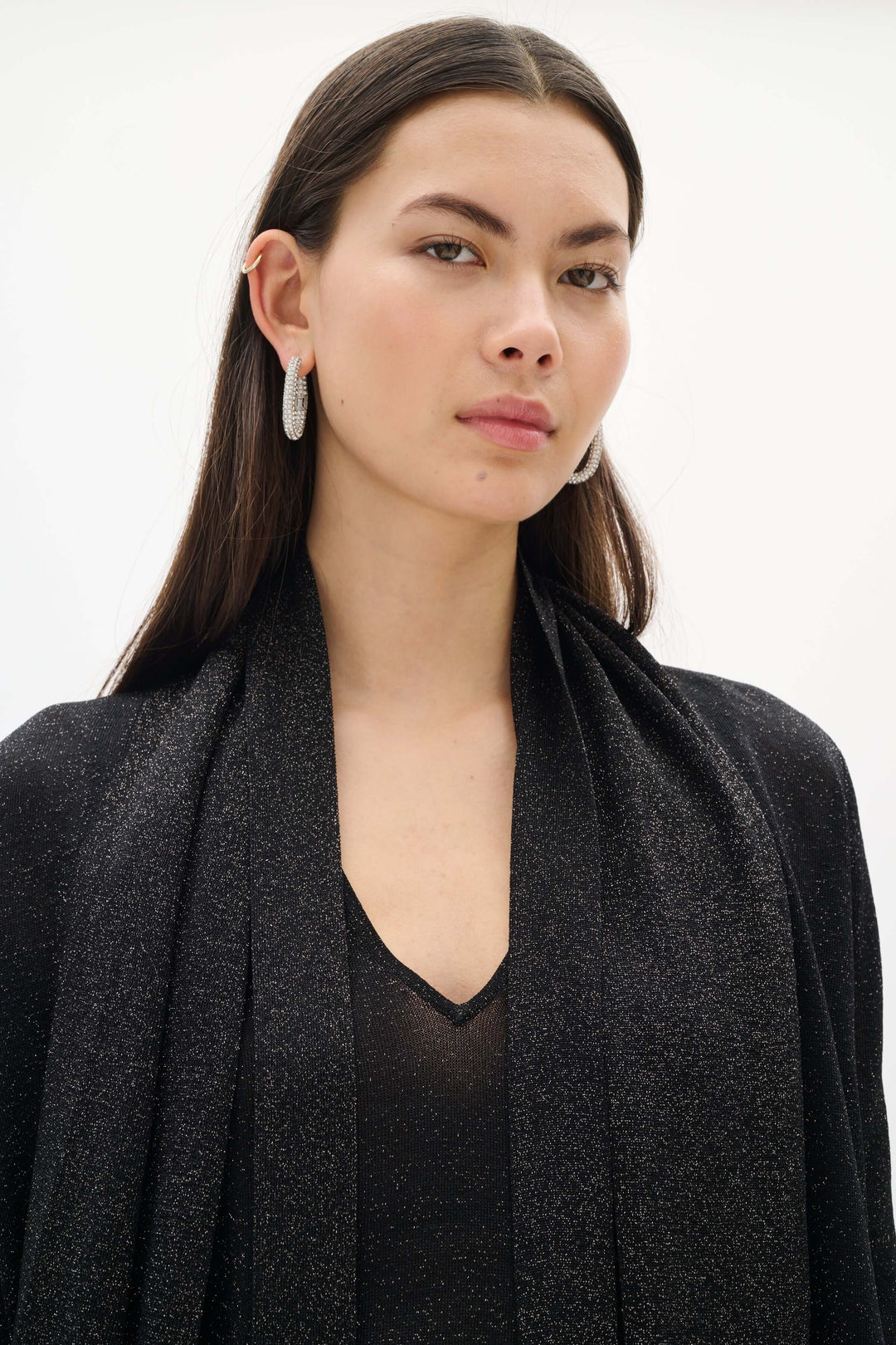 Femme portant un Cardigan Thani à effet scintillant avec foulard intégré, tissu lumineux et élégant, pour un look sophistiqué.