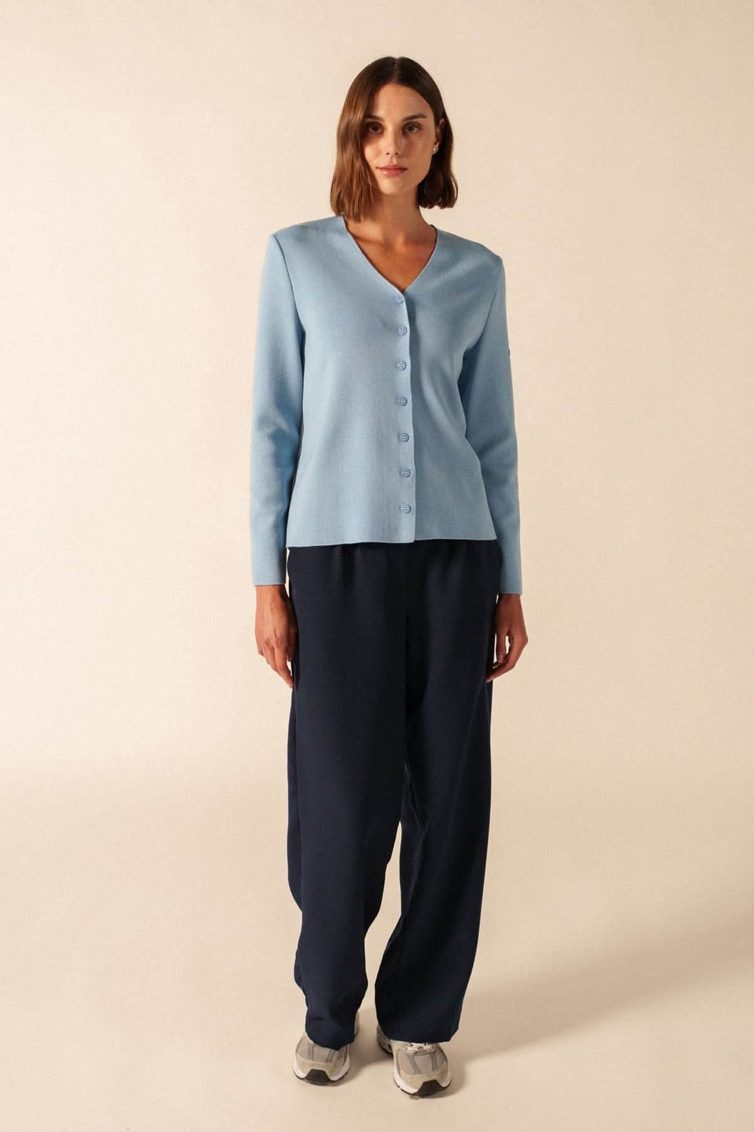 Femme portant le cardigan de laine BREVANDS bleu avec encolure en V minimaliste et boutons discrets, style élégant et polyvalent.