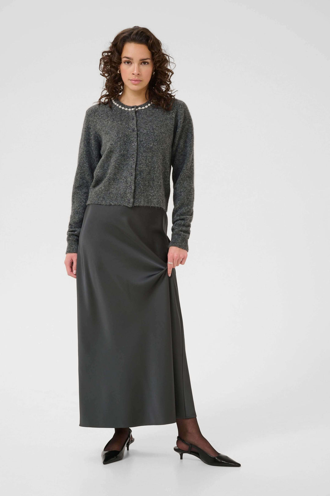 Femme portant un Cardigan en laine bouclée à col orné avec une jupe longue élégante.