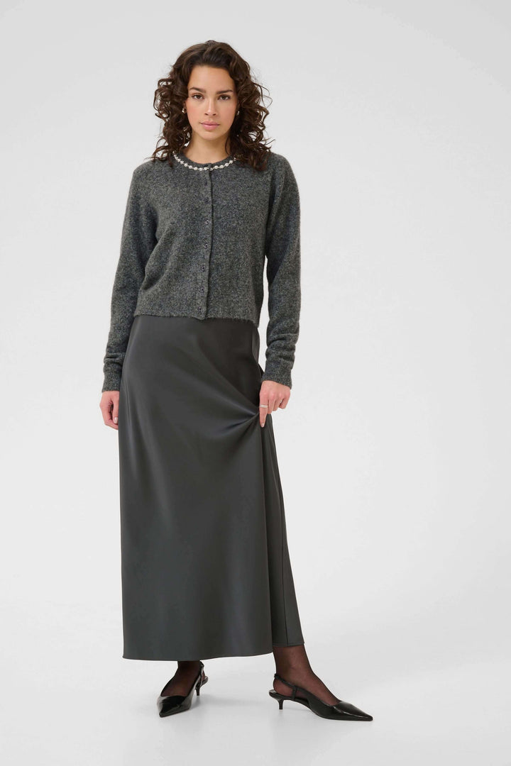 Femme portant un Cardigan en laine bouclée à col orné avec une jupe longue élégante.