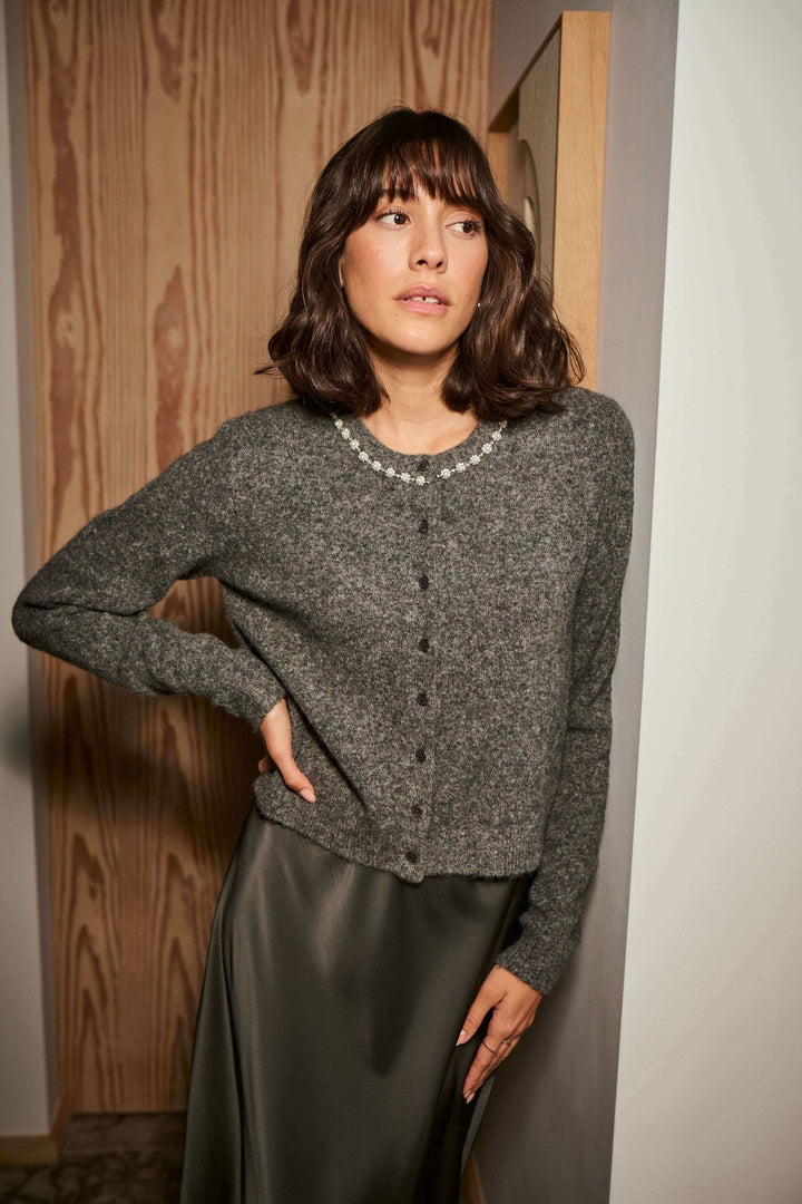 Femme portant un cardigan en laine bouclée à col orné avec perles, idéal pour une tenue élégante et féminine.