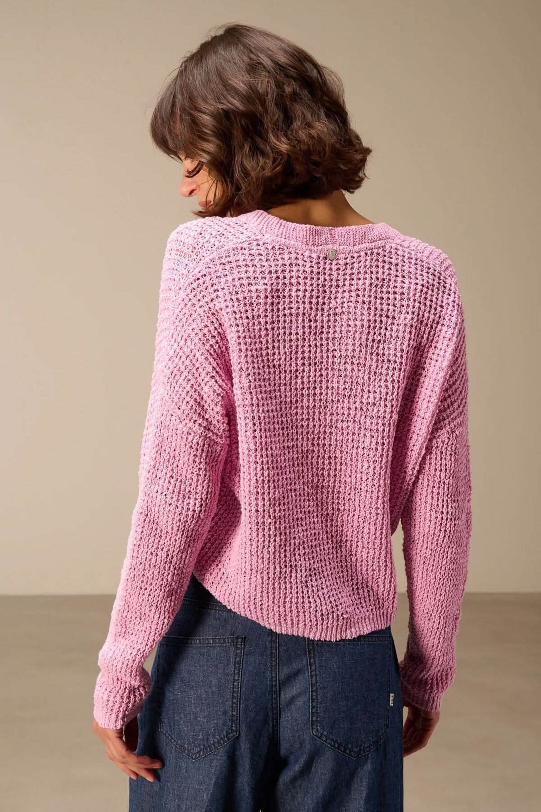Cardigan en maille texturée à col en V rose, vu de dos, avec manches longues et finitions côtelées, porté par une femme.