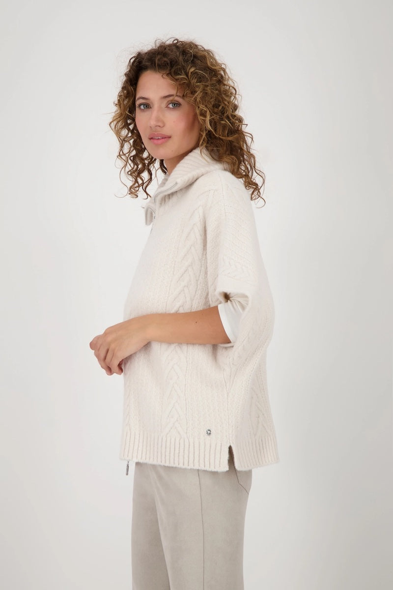Cardigan en maille torsadée coloris beige, coupe oversize avec col roulé et fermeture éclair, stylé et confortable.