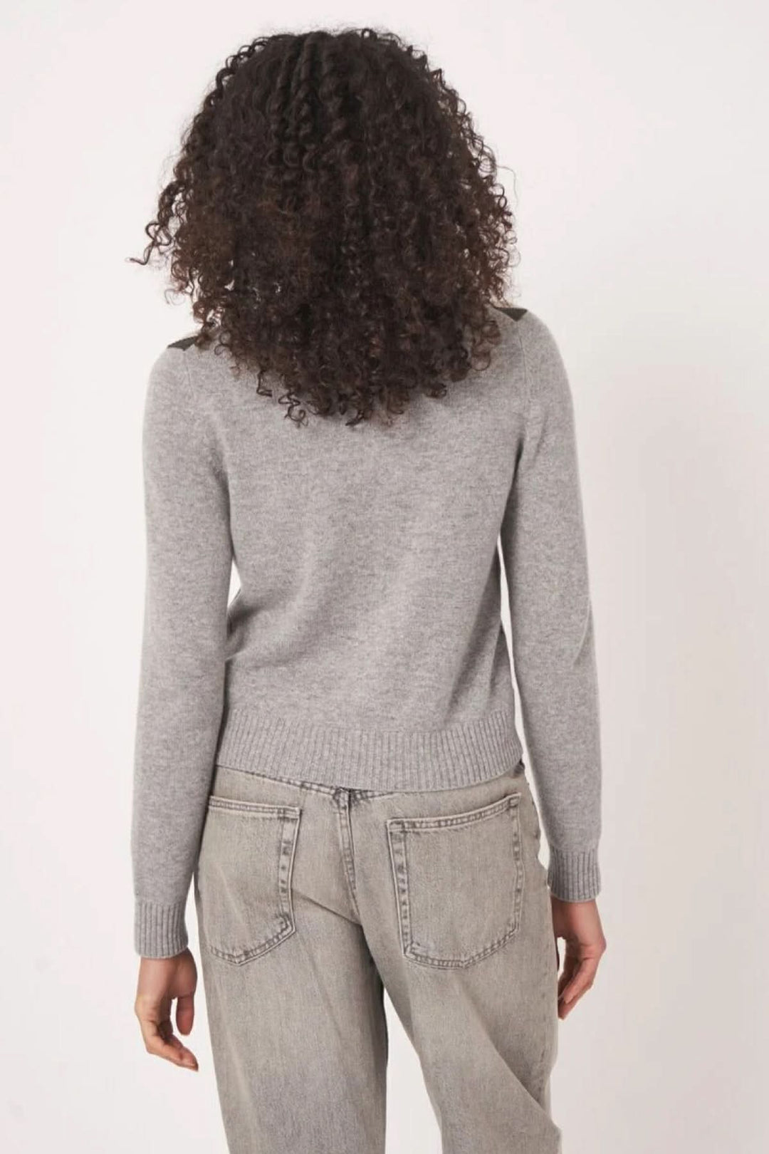 Cardigan à motif gris avec dos simple, combiné avec un pantalon, mettant en avant une allure moderne et rétro.
