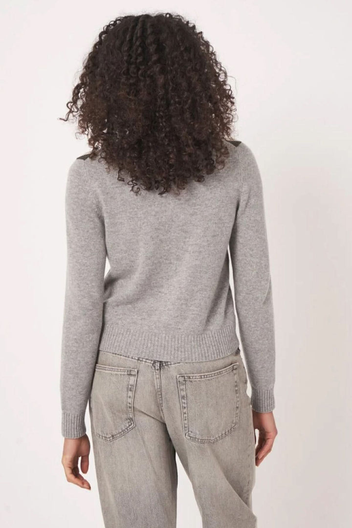 Cardigan à motif gris avec dos simple, combiné avec un pantalon, mettant en avant une allure moderne et rétro.