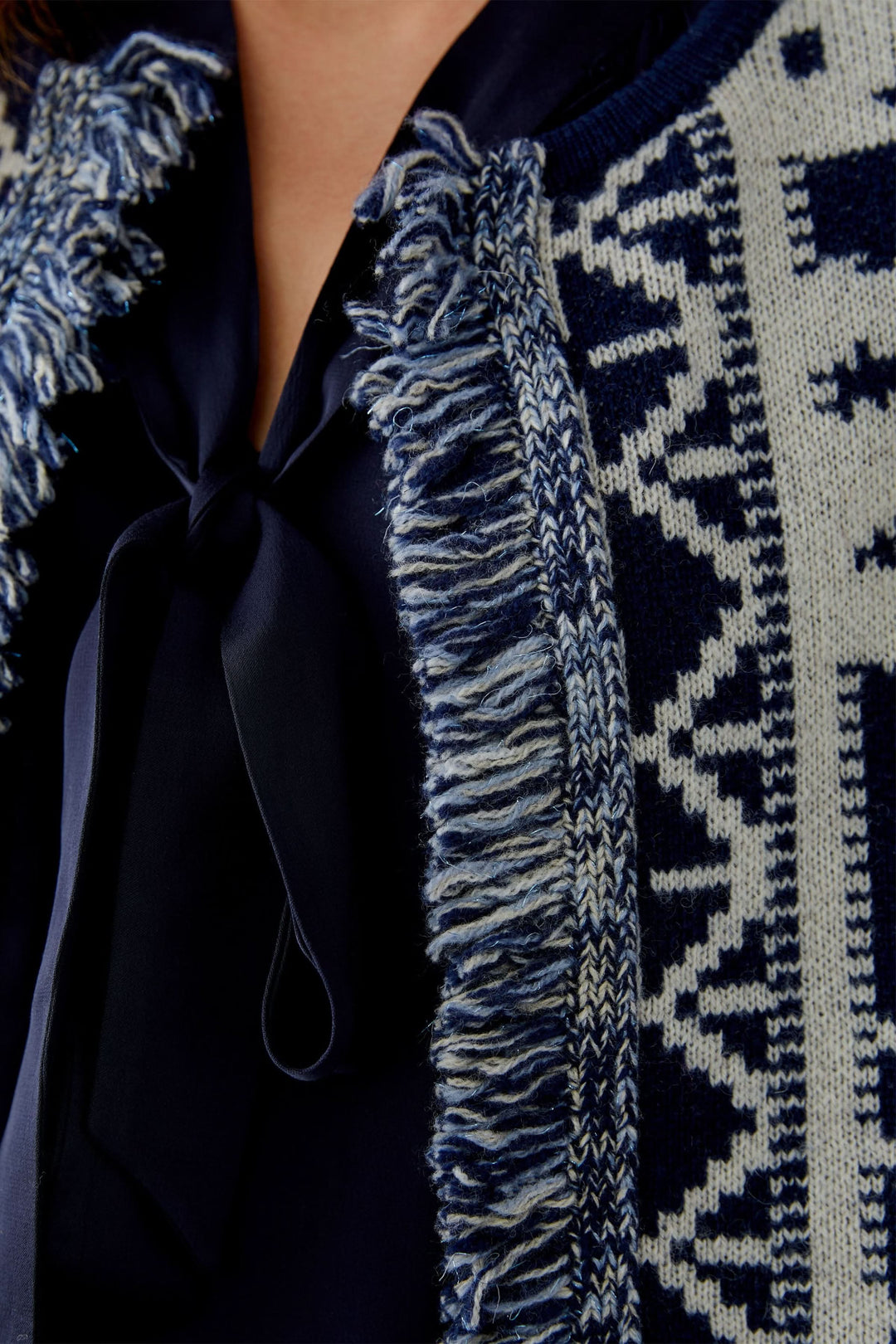 Gros plan sur un cardigan motif western avec franges décoratives et col rond, alliant confort et style.