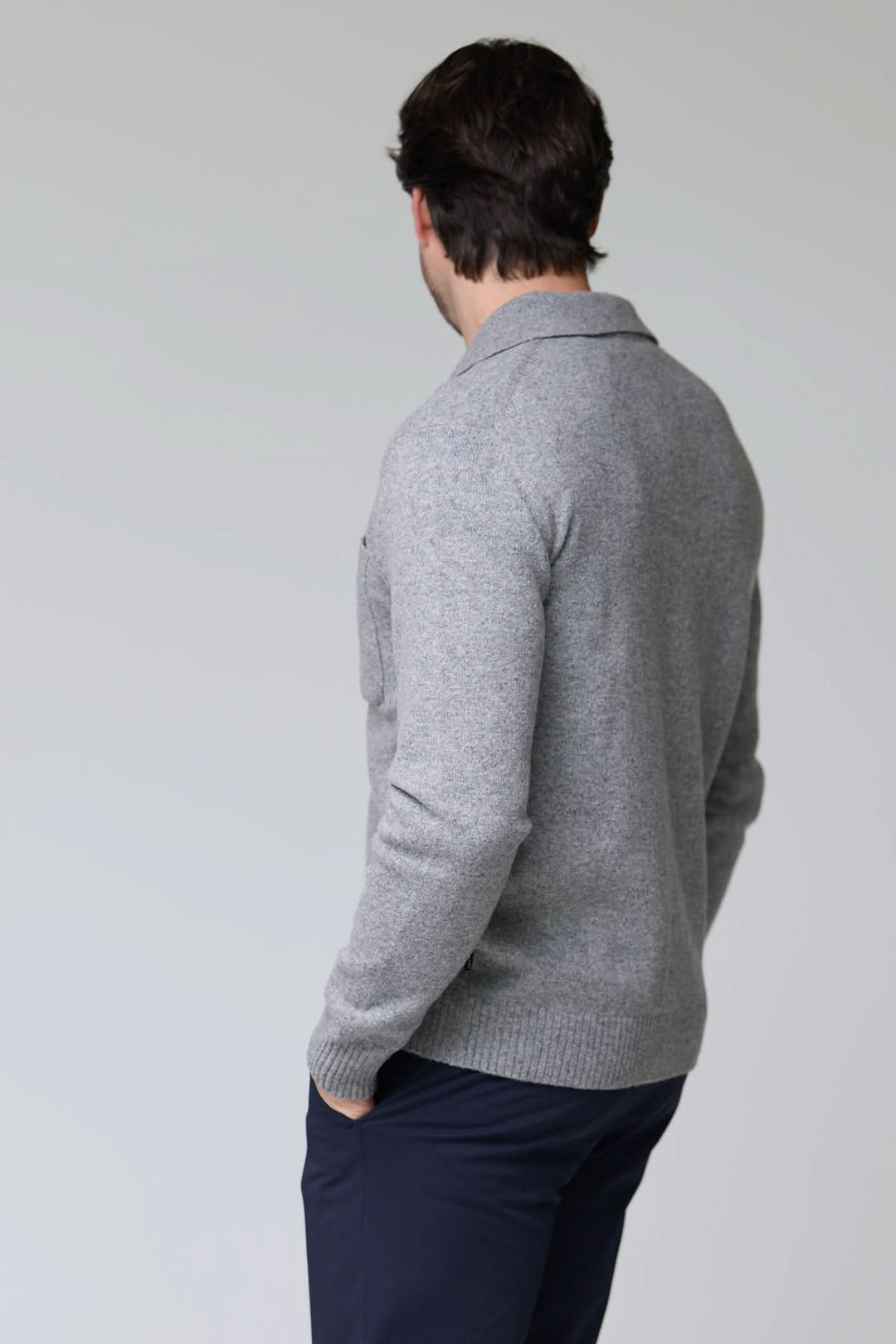 Homme portant un cardigan à poches plaquées en laine, vue de dos, affichant un tricot dense et côtelé gris.