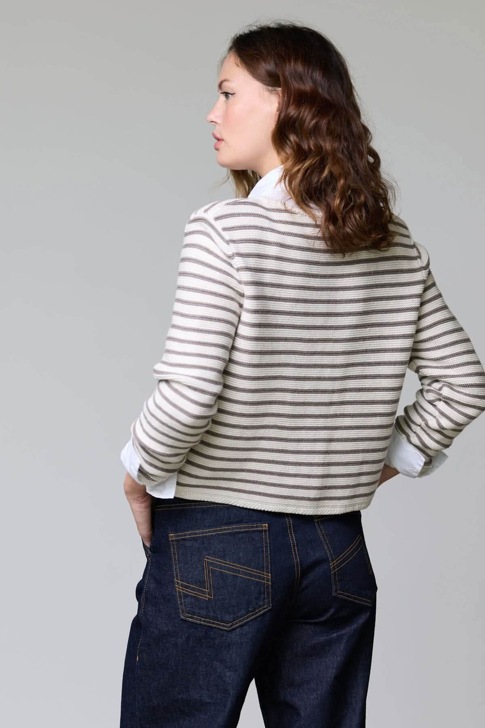 Femme portant un cardigan rayé court à boutons en maille douce, vue de dos, parfait pour un style marin chic et décontracté.