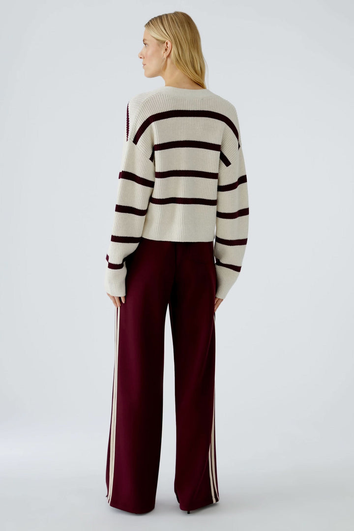 Cardigan à rayures modernes avec maille côtelée, porté avec un pantalon fluide, vue arrière.