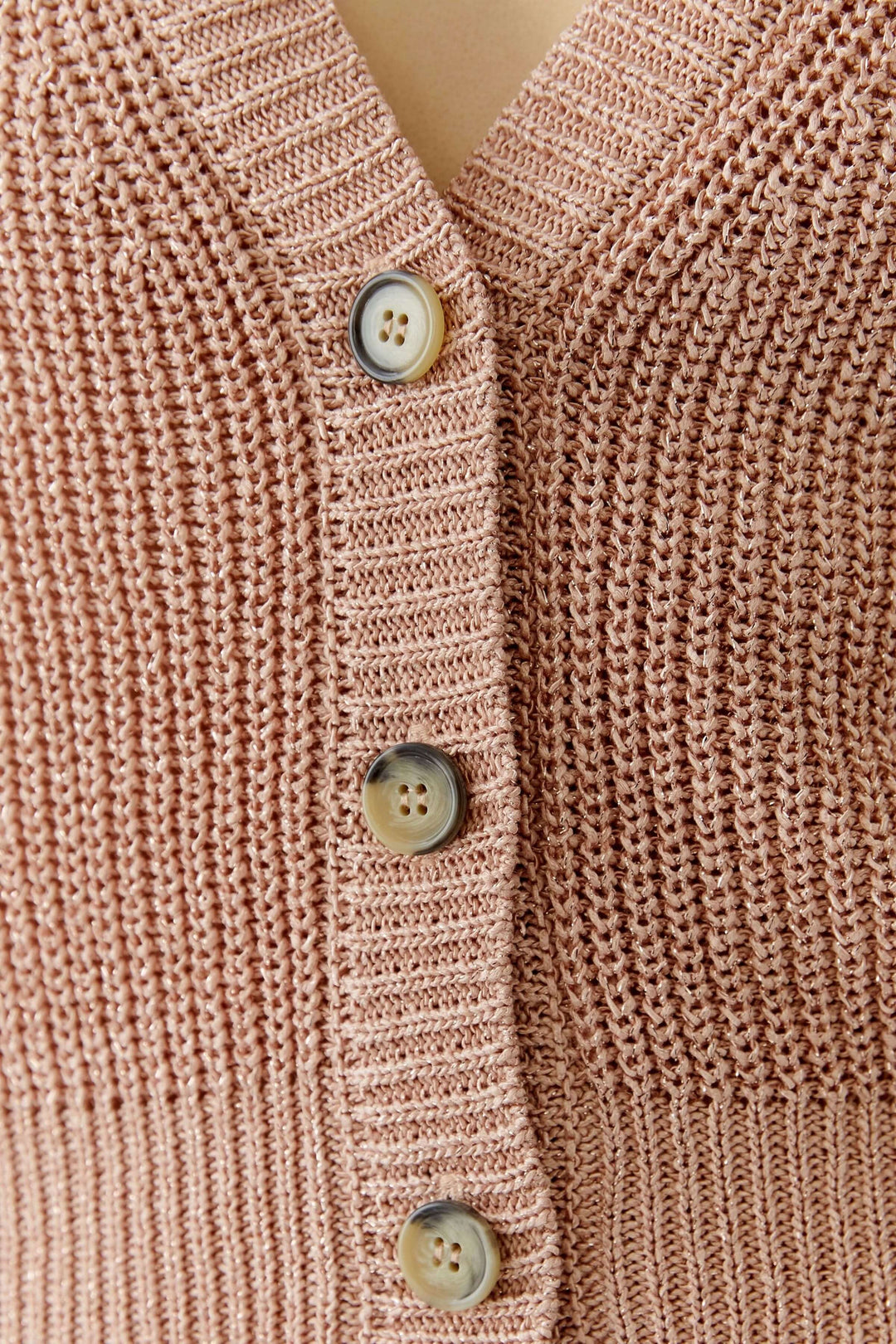 Gros plan sur le cardigan tricoté avec boutons classiques et encolure en V élégante pour une silhouette raffinée.