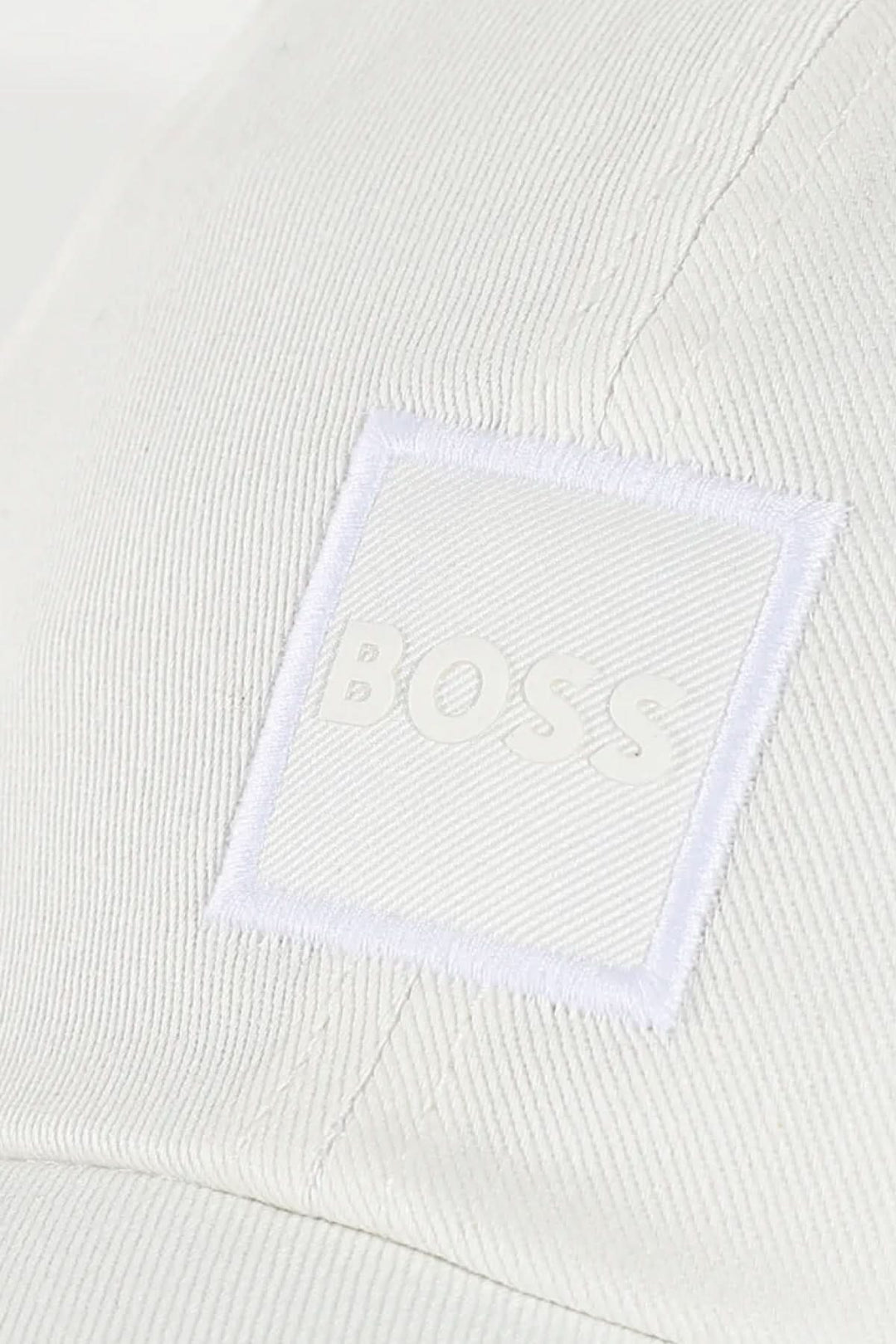 Écusson ton sur ton de la casquette BOSS sur tissu blanc, ajoutant une touche de style contemporain.
