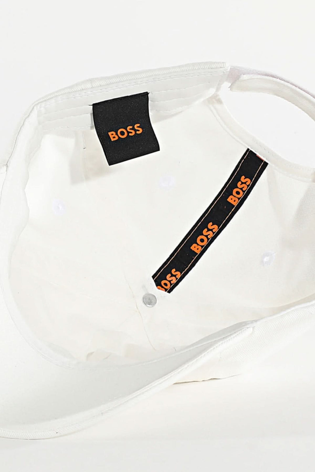 Détail intérieur de la casquette BOSS avec étiquette et bandeau noir et orange.