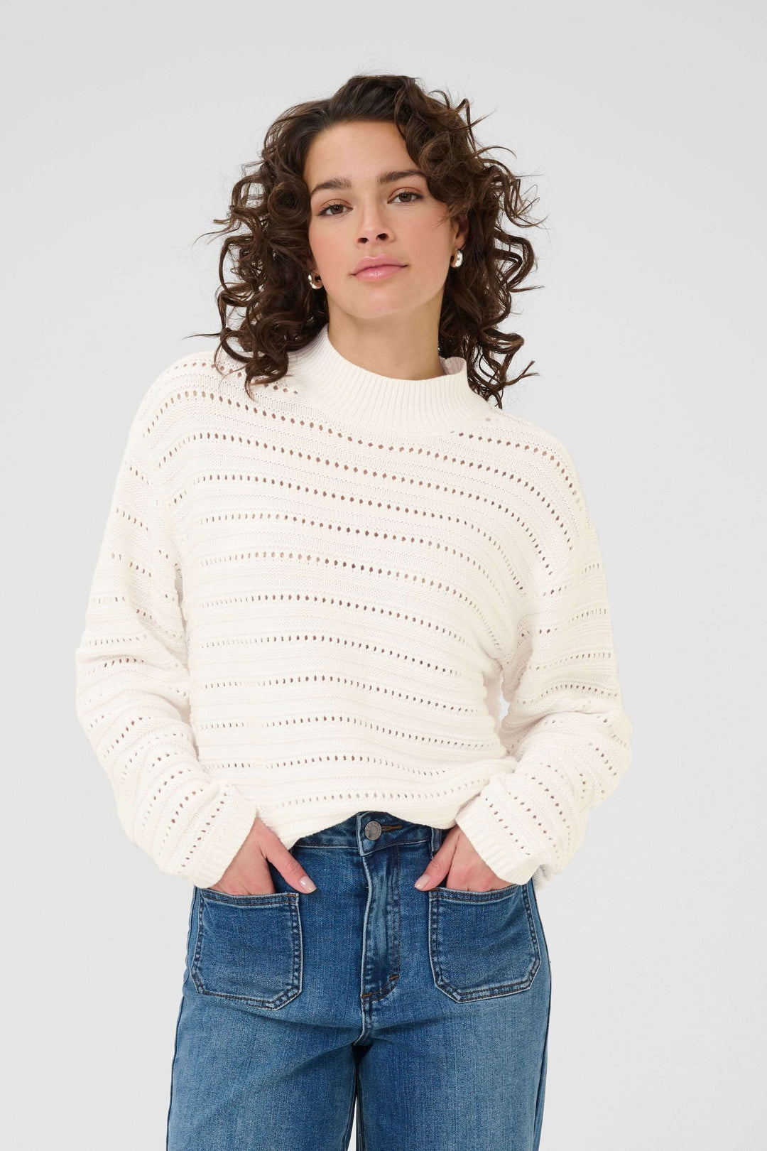 Femme portant un Chandail Dolly en tricot ajouré avec un motif élégant, col montant et manches longues, combiné avec un jean.