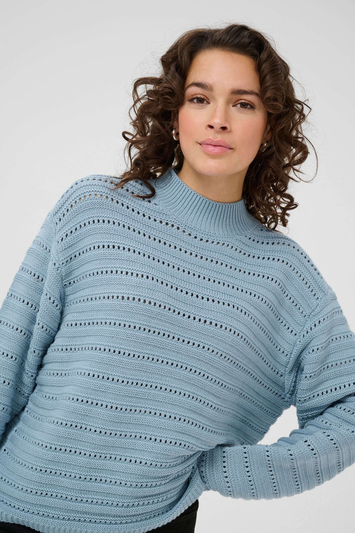 Femme portant le Chandail Dolly en tricot ajouré bleu avec col montant côtelé.