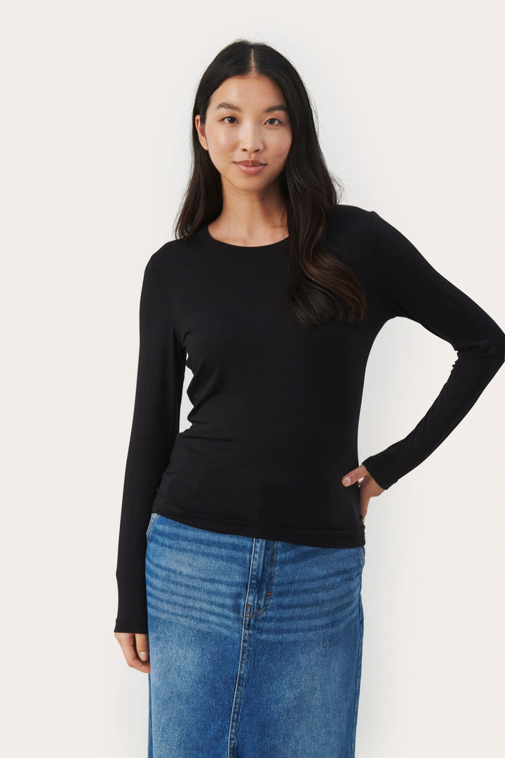 Chandail Emaja noir à manches longues, encolure ronde, style ajusté, porté avec une jupe en denim.