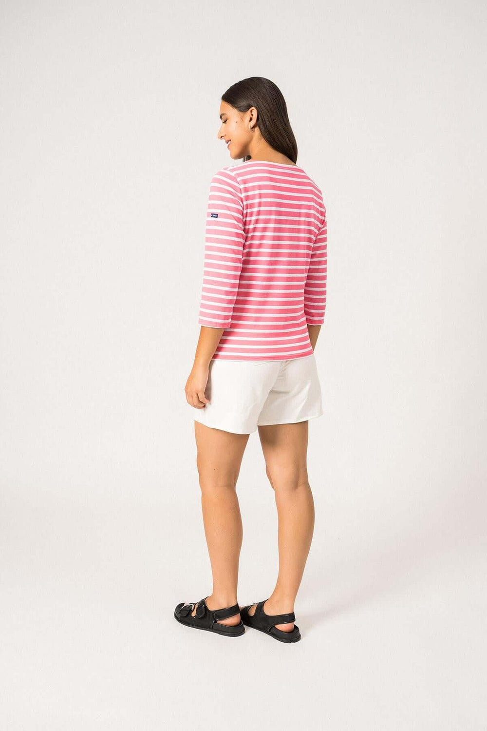 Femme vue de dos portant un chandail GALATHEE II rayé rose avec manches ¾ et short blanc.