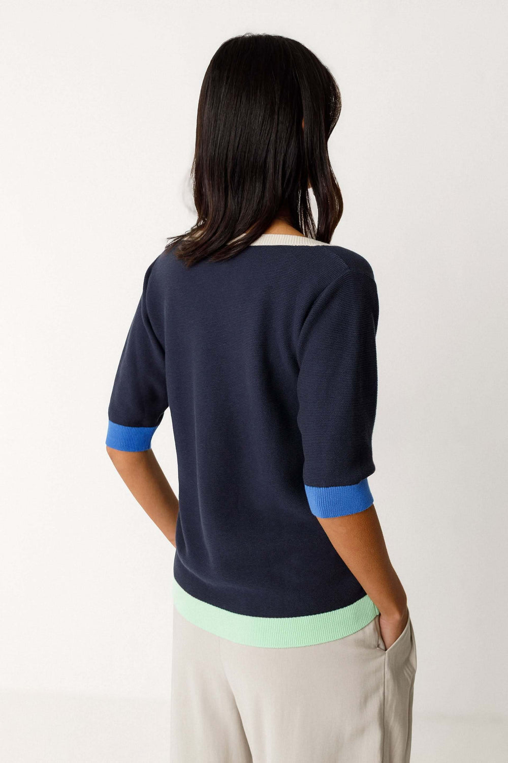 Dos d'une femme portant le Chandail Lary tricot léger col rond manches courtes avec détails contrastants en bleu et vert.