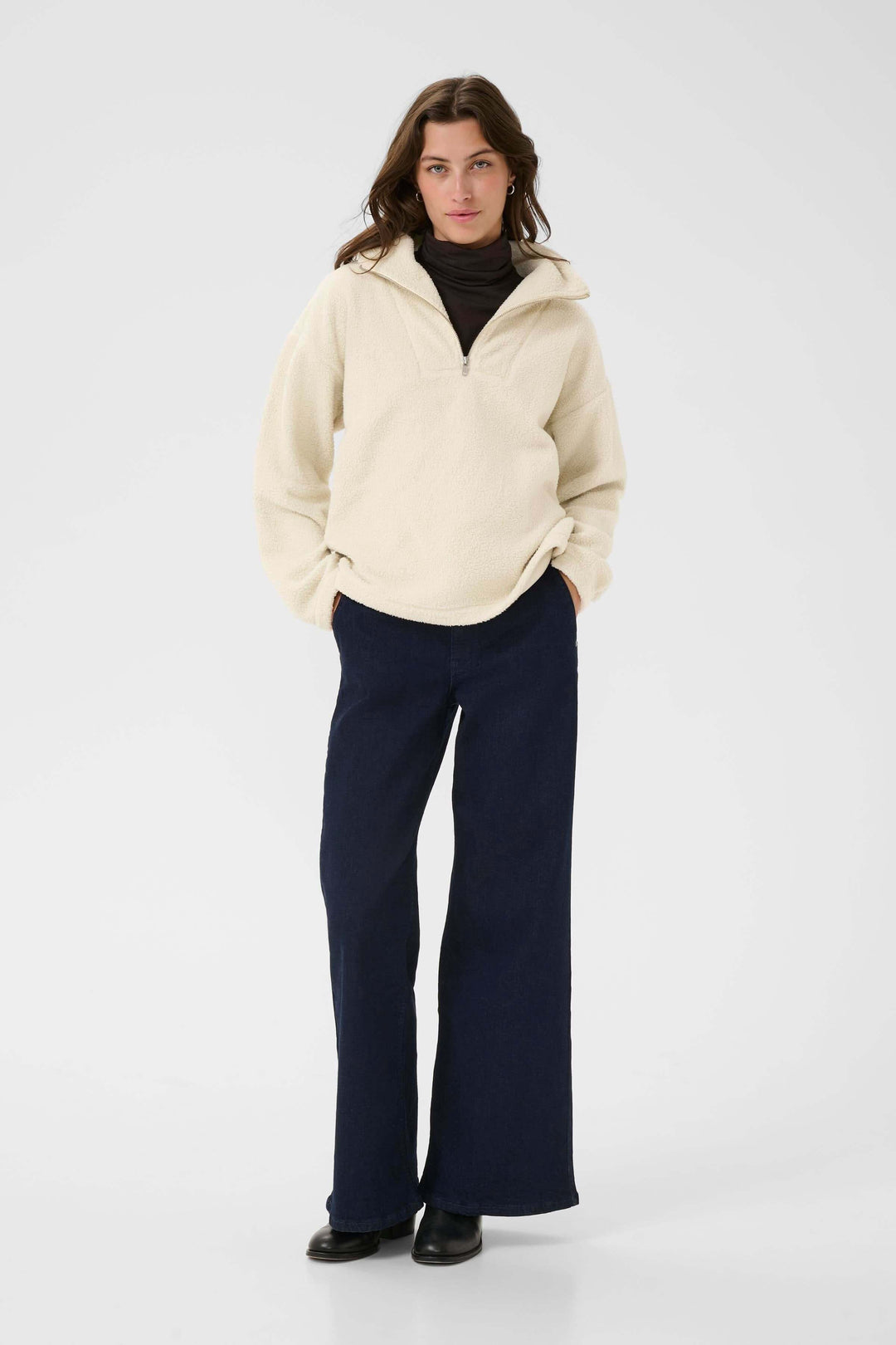 Femme portant le Chandail Sirana en tissu sherpa beige avec col montant zippé, style décontracté pour la mi-saison.