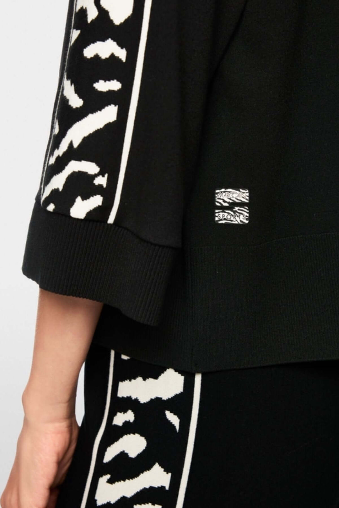 Chandail ample avec manches larges et motif animalier contrasté, détail de la bande et bords-côtes, label « Rethink Together » visible.