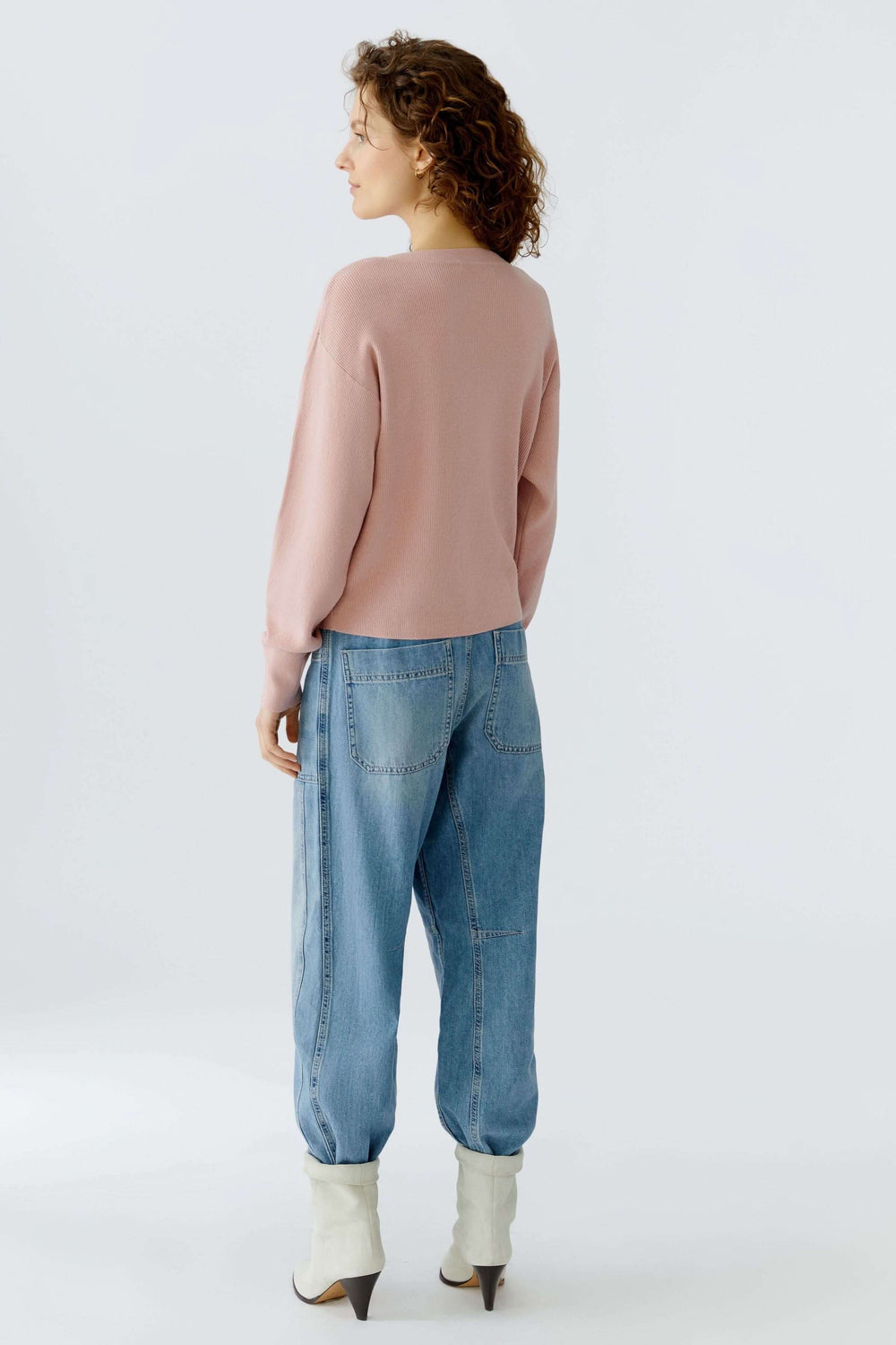 Chandail avec un détail de nœud spécial à l'ourlet, porté avec un jean pour un look moderne et féminin.