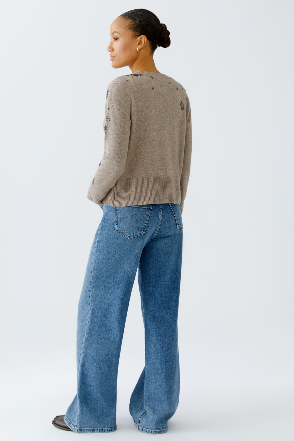 Femme portant un chandail broderies beige avec jean, vue arrière, illustrant le style quotidien du chandail tricote doux et brodé.