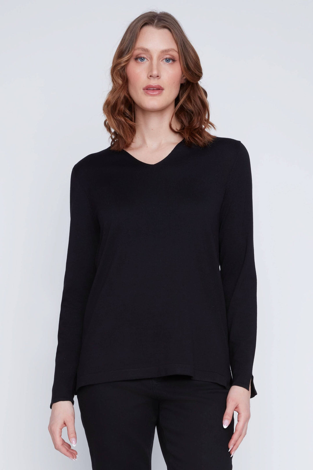 Femme portant un chandail col V noir à manches longues, style minimaliste et coupe fluide. Chandail col V idéal pour un look chic.