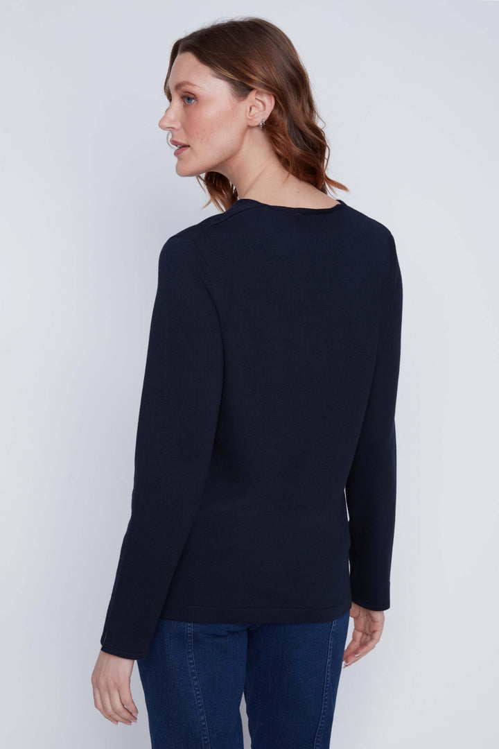 Femme portant un chandail col V à manches longues, coupe fluide et maille douce, vue de dos, tenue chic et minimaliste.