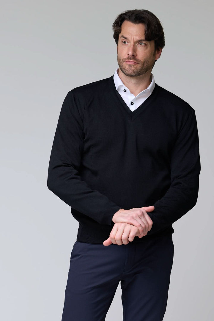 Homme portant un chandail col en V en laine mérinos noir sur chemise blanche élégante