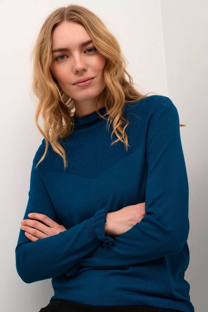 Chandail à col montant bleu avec détails ajourés au niveau des épaules, coupe fluide et élégante.
