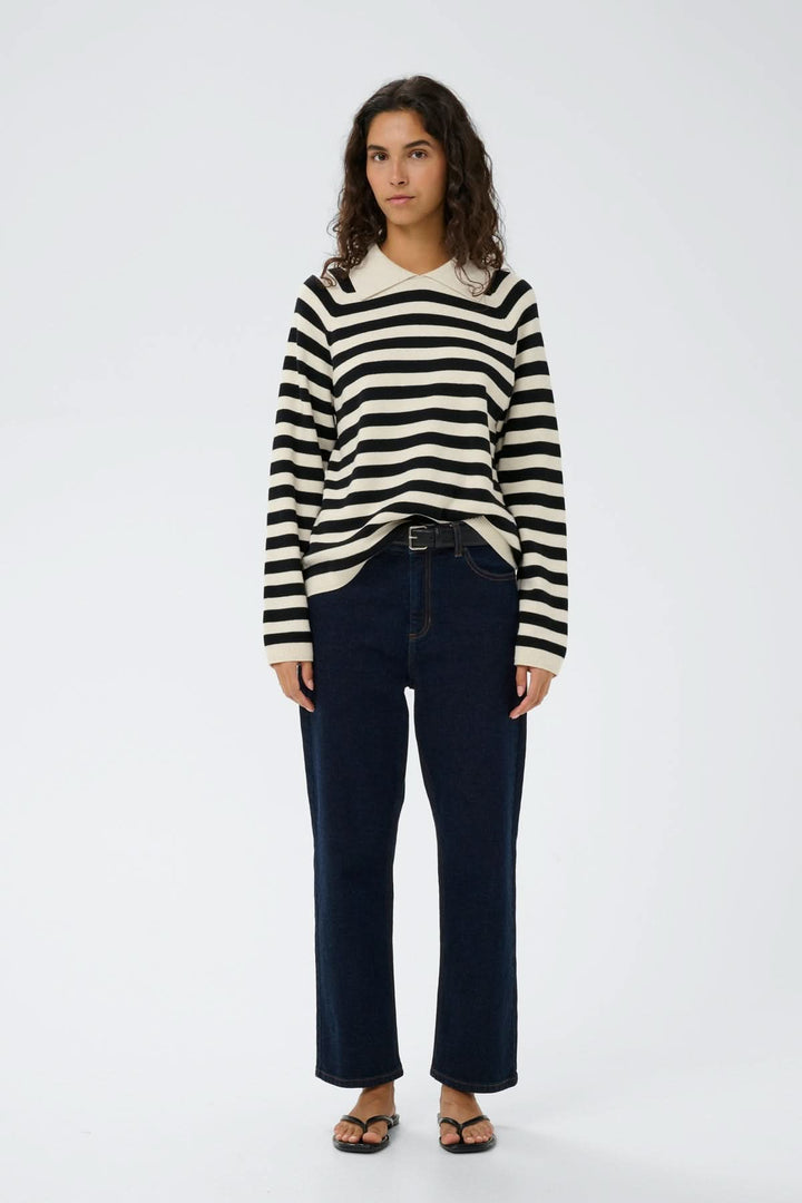 Femme portant un Chandail rayé à col polo Madie, coupe droite, style décontracté, rayures noires et blanches, manches longues.