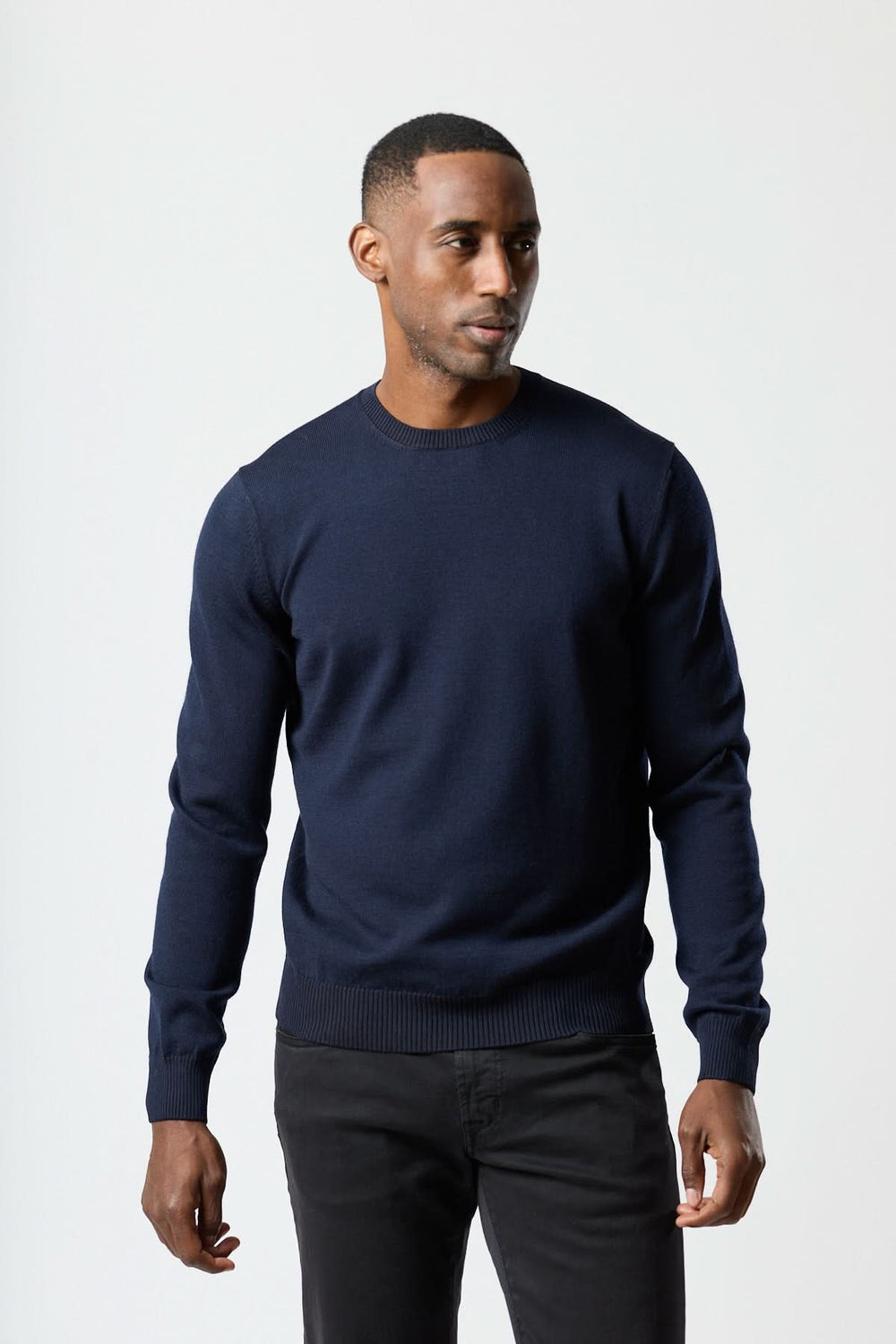 Homme portant un chandail col rond essentiel de couleur bleue, confortable et moderne, parfait pour un look élégant et décontracté.