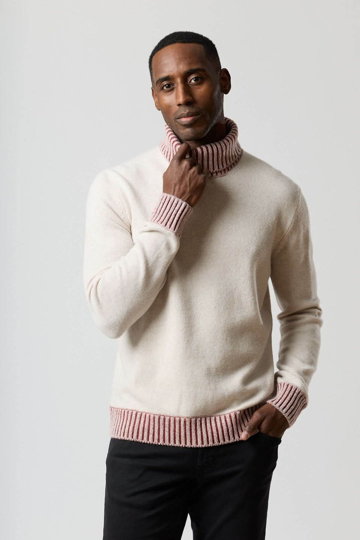 Homme portant un chandail col roulé à côtes contrastées crème et rose avec une finition élégante.