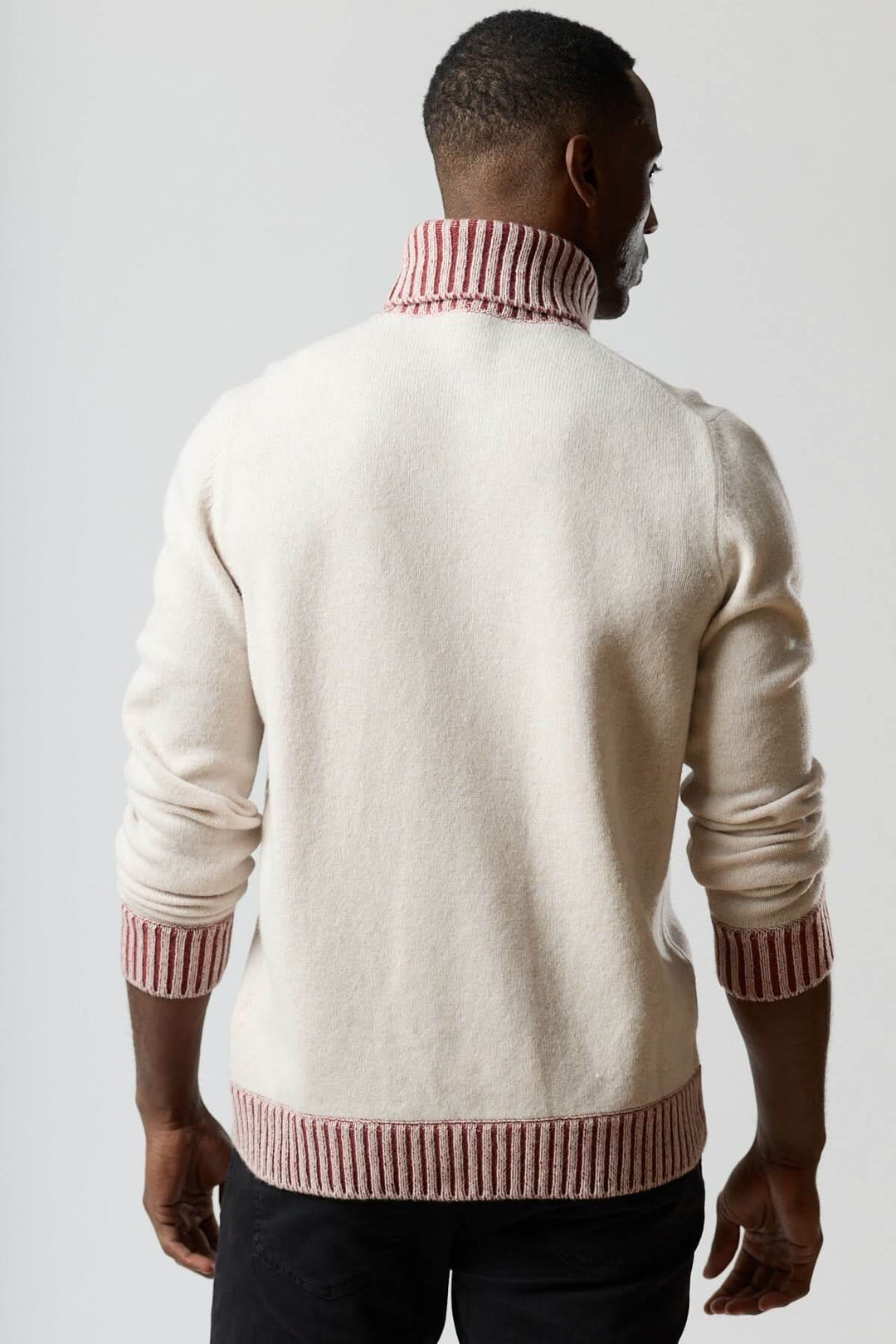 Homme portant un chandail col roulé à côtes contrastées, vue arrière, soulignant le design en maille et bords rouges.